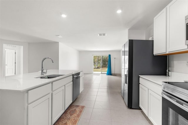 kitchen featuring white cabinets, sink, an island with sink, appliances with stainless steel finishes, and light tile patterned flooring