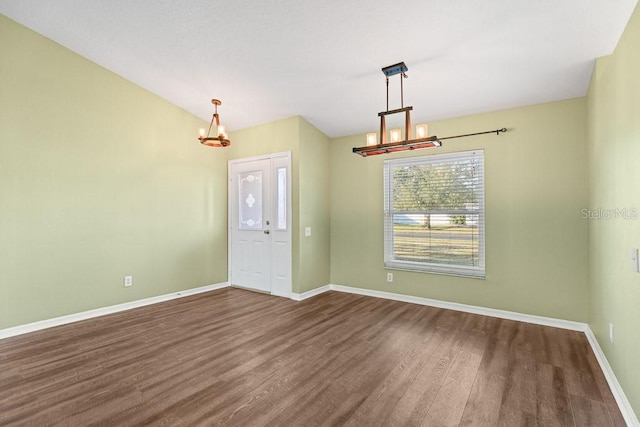 empty room featuring a notable chandelier and dark hardwood / wood-style flooring