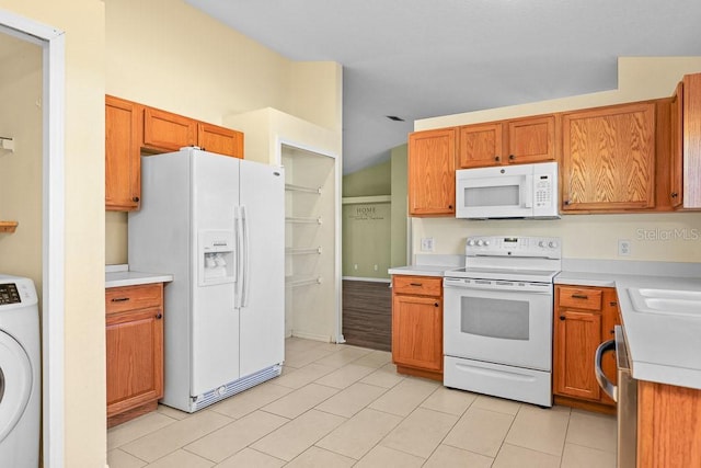 kitchen with washer / dryer, white appliances, light tile patterned floors, and lofted ceiling