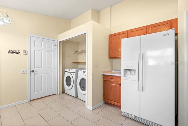 clothes washing area featuring washing machine and dryer and light tile patterned floors