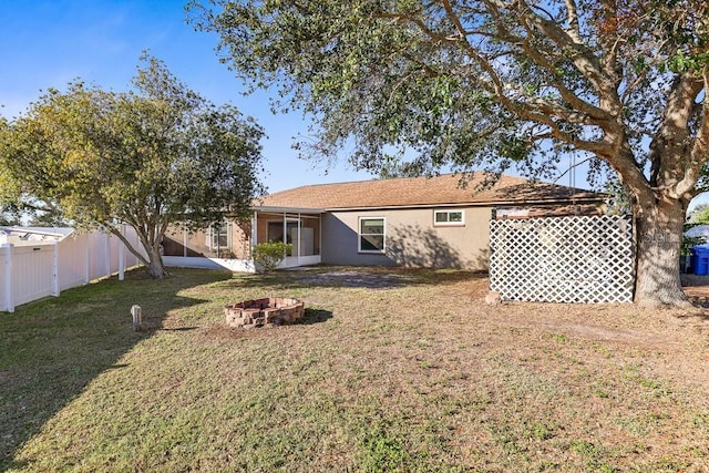 rear view of property with a sunroom, a fire pit, and a yard