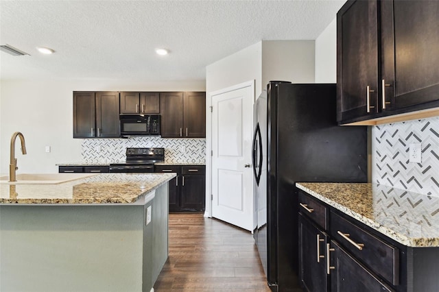 kitchen featuring sink, tasteful backsplash, light stone counters, and black appliances