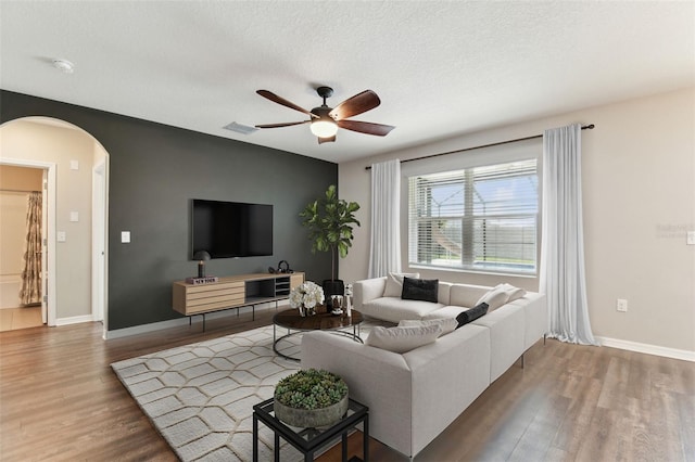 living room with ceiling fan, wood-type flooring, and a textured ceiling