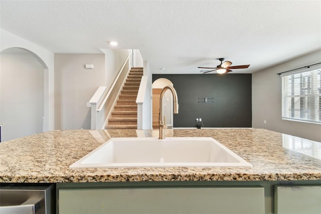 kitchen with green cabinets, ceiling fan, sink, and a textured ceiling