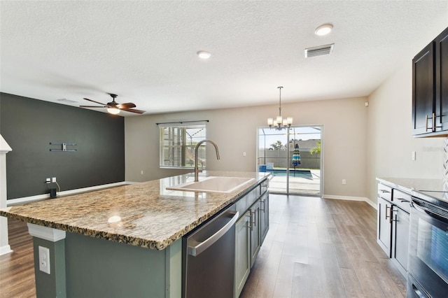 kitchen featuring range with electric cooktop, dishwasher, sink, hanging light fixtures, and a kitchen island with sink