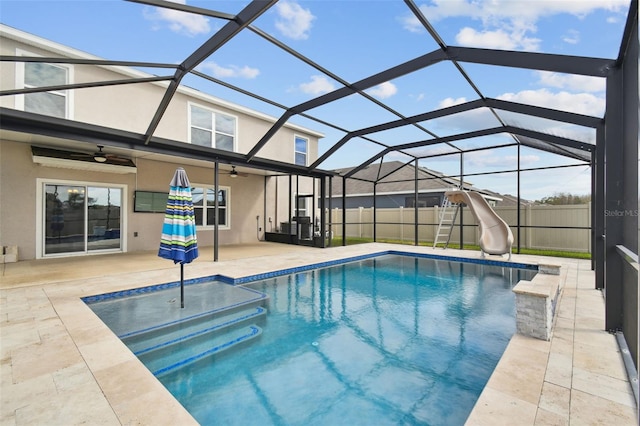 view of pool with glass enclosure, ceiling fan, a patio, and a water slide