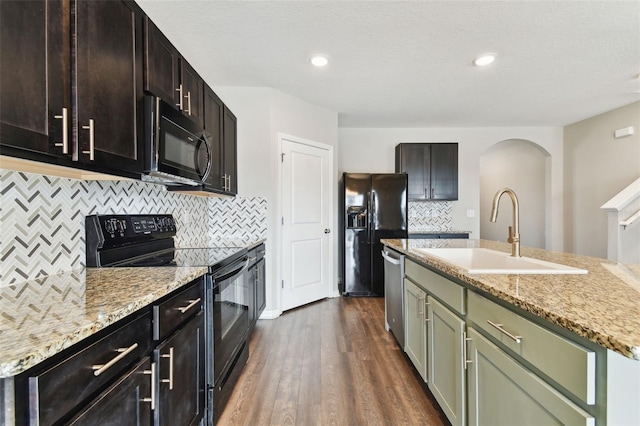 kitchen featuring black appliances, decorative backsplash, sink, and an island with sink