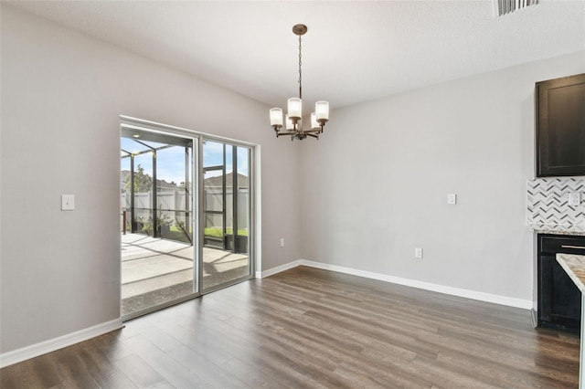 unfurnished dining area featuring a textured ceiling, a chandelier, and dark hardwood / wood-style floors