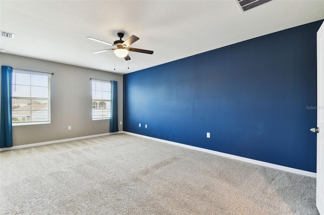 empty room featuring ceiling fan, light colored carpet, and a textured ceiling