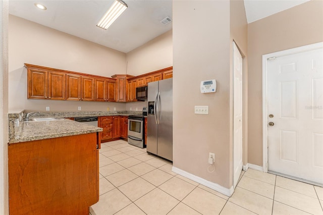 kitchen featuring a towering ceiling, sink, light stone counters, light tile patterned floors, and appliances with stainless steel finishes