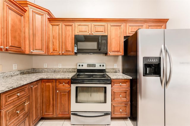 kitchen featuring light tile patterned flooring, light stone countertops, and stainless steel appliances