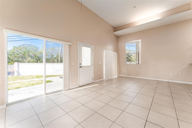 unfurnished room featuring a towering ceiling and light tile patterned flooring