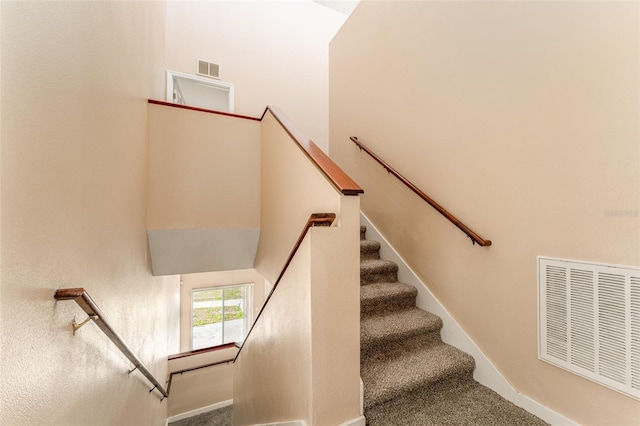 staircase featuring carpet and a towering ceiling