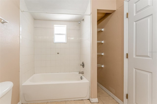 bathroom with toilet, tile patterned flooring, and tiled shower / bath combo