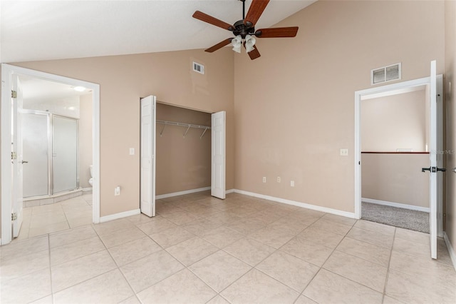 unfurnished bedroom featuring light tile patterned floors, a closet, ensuite bathroom, ceiling fan, and high vaulted ceiling