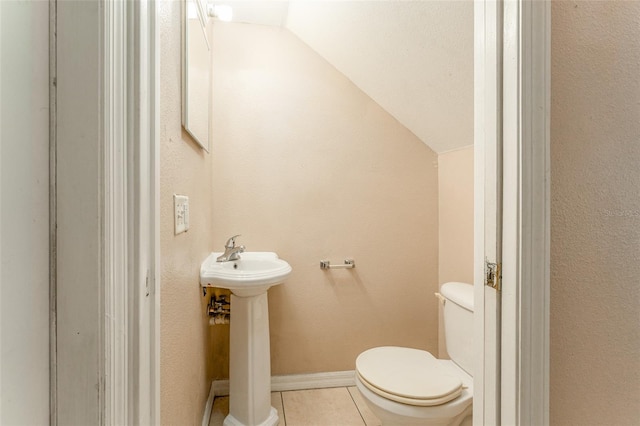 bathroom with tile patterned floors, vaulted ceiling, sink, and toilet