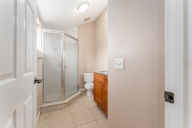 bathroom featuring toilet, vanity, tile patterned flooring, and walk in shower