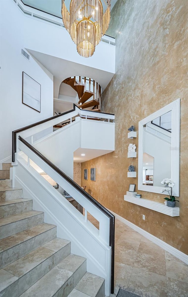 staircase featuring an inviting chandelier and a towering ceiling