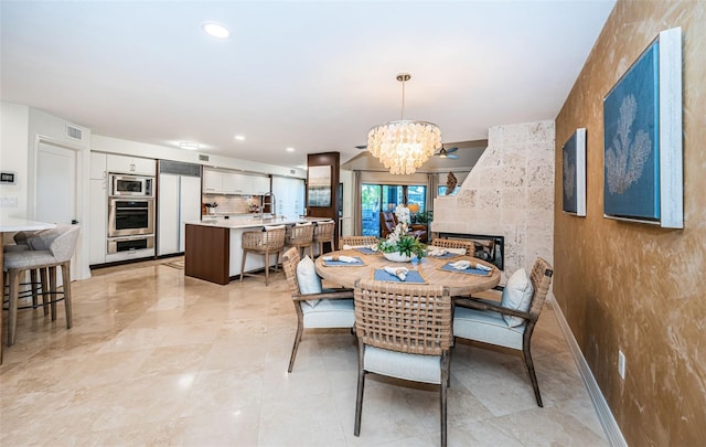 dining area with a multi sided fireplace, sink, and a notable chandelier