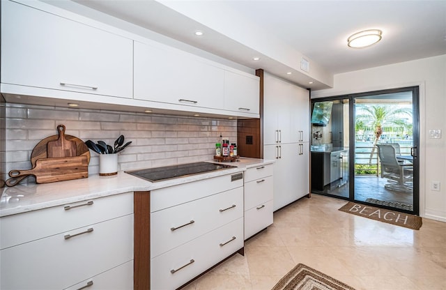 kitchen featuring black electric cooktop, backsplash, and white cabinets