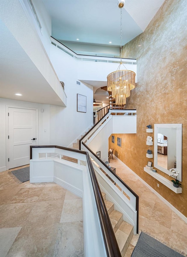 staircase with a towering ceiling and a chandelier