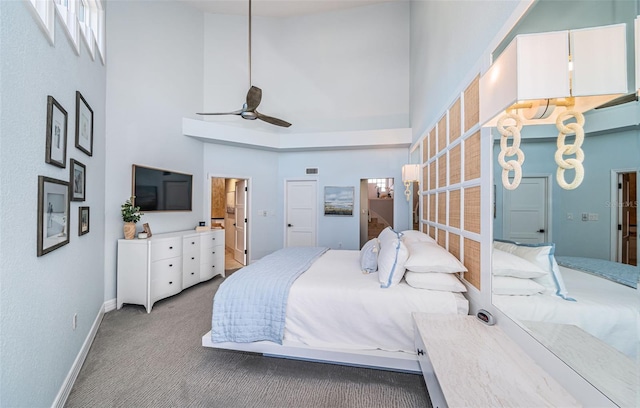 bedroom featuring ceiling fan, light carpet, and a high ceiling