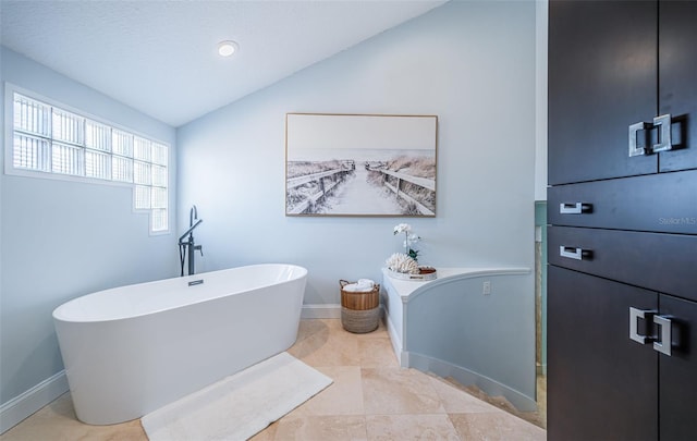 bathroom featuring tile patterned floors, lofted ceiling, and a bath