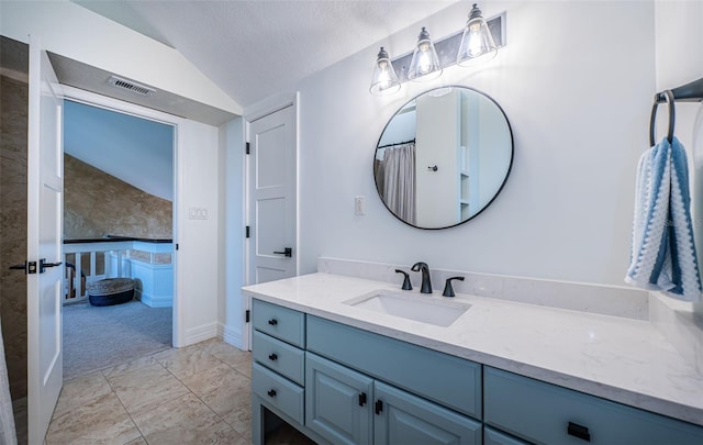 bathroom with vaulted ceiling, vanity, and a textured ceiling