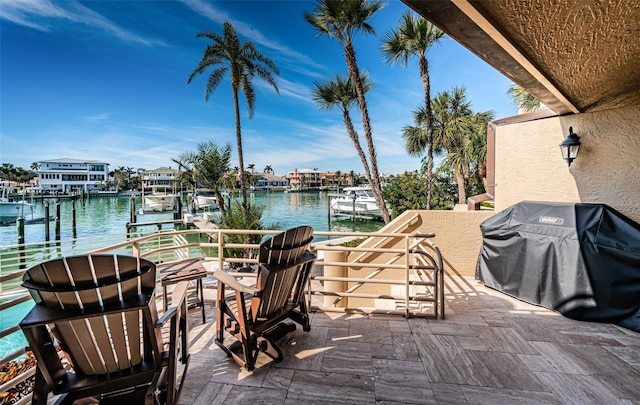 view of patio featuring a water view, a grill, and a dock