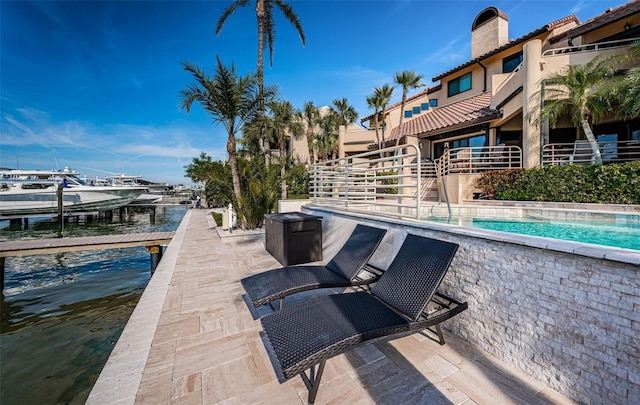 view of patio with a water view, a community pool, and a dock