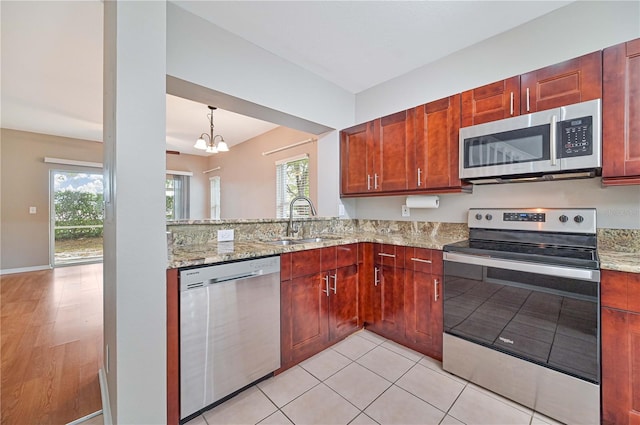 kitchen featuring light stone countertops, appliances with stainless steel finishes, sink, light tile patterned floors, and an inviting chandelier