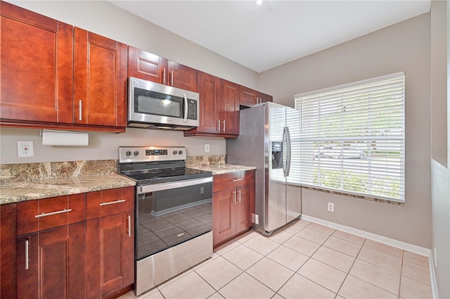 kitchen featuring light stone counters, light tile patterned floors, and stainless steel appliances