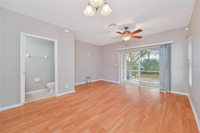 unfurnished room with ceiling fan with notable chandelier and light hardwood / wood-style floors