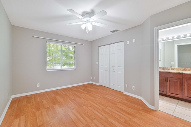 unfurnished bedroom with ensuite bath, ceiling fan, sink, a closet, and light wood-type flooring