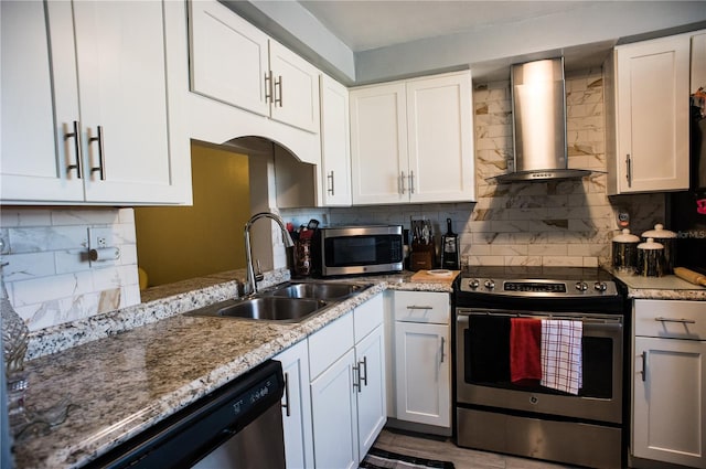 kitchen featuring white cabinets, stainless steel appliances, and wall chimney range hood