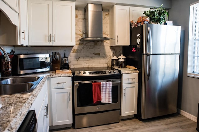 kitchen featuring white cabinets, appliances with stainless steel finishes, and wall chimney range hood