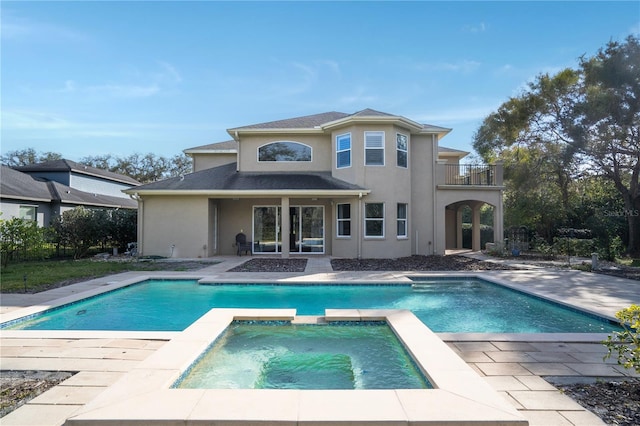 rear view of house featuring a balcony, a pool with hot tub, and a patio