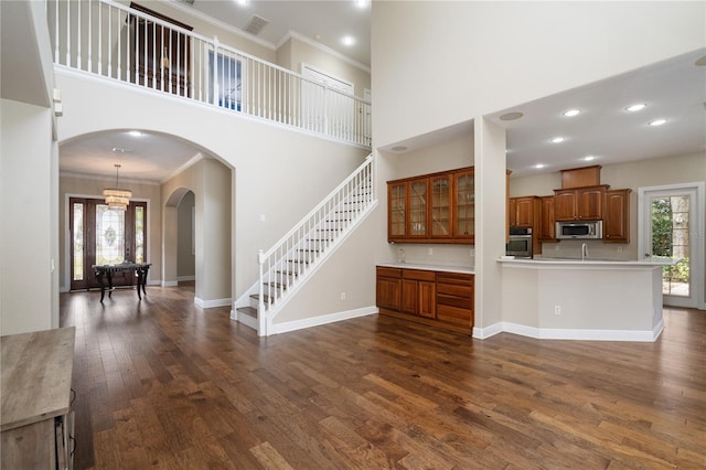 unfurnished living room featuring dark hardwood / wood-style flooring, crown molding, and a high ceiling