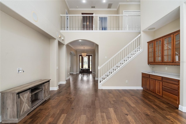 foyer featuring dark hardwood / wood-style flooring, crown molding, and a towering ceiling