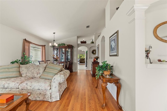 living room with vaulted ceiling, a notable chandelier, and light hardwood / wood-style flooring