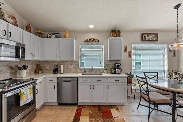 kitchen featuring light tile patterned flooring, sink, white cabinetry, pendant lighting, and stainless steel appliances