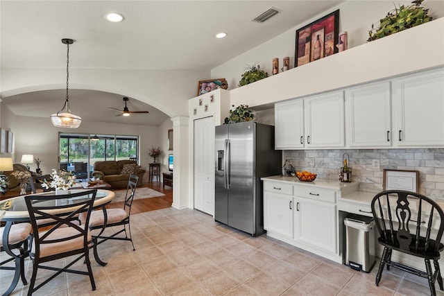 kitchen with white cabinetry, stainless steel fridge, decorative light fixtures, and tasteful backsplash