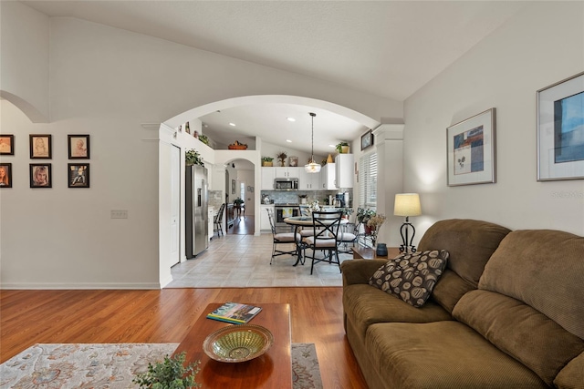 living room featuring lofted ceiling and light hardwood / wood-style floors