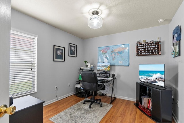 office space featuring plenty of natural light, a textured ceiling, and light hardwood / wood-style floors