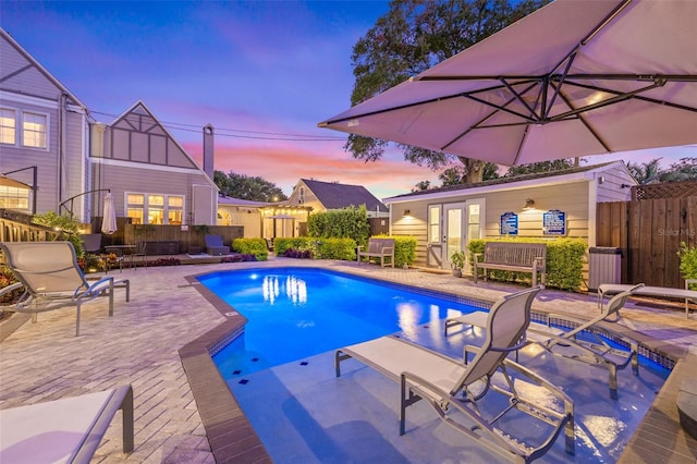 pool at dusk featuring a patio area