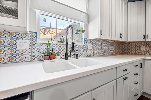 kitchen with backsplash, white cabinetry, and sink