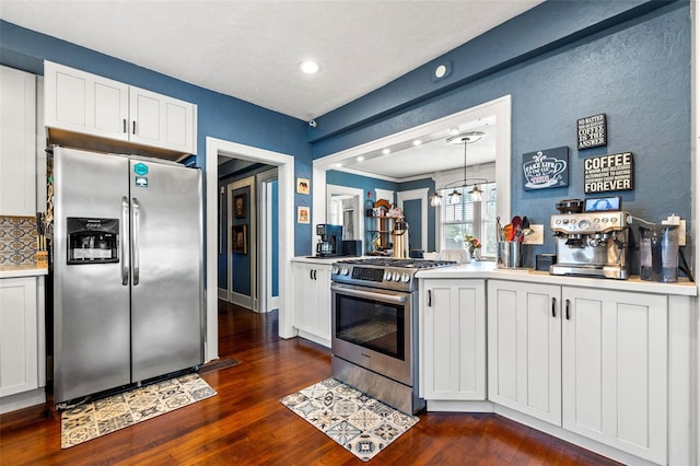 kitchen featuring dark hardwood / wood-style flooring, tasteful backsplash, stainless steel appliances, white cabinets, and hanging light fixtures