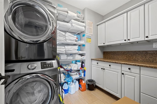 clothes washing area with stacked washer / dryer and cabinets