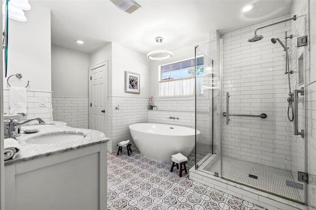 bathroom featuring tile patterned flooring, vanity, shower with separate bathtub, and tile walls