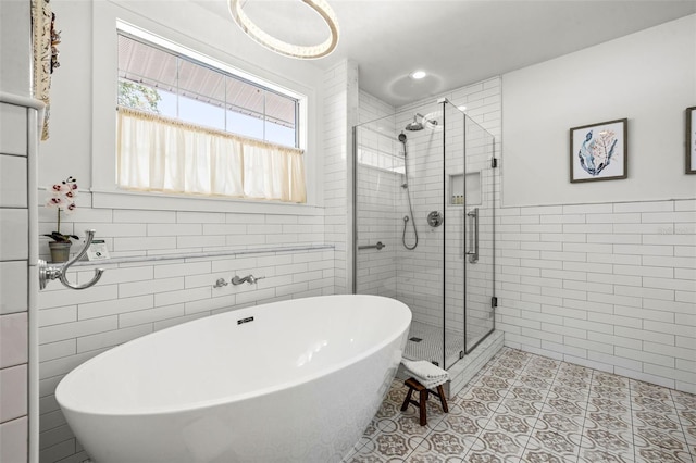 bathroom featuring tile patterned flooring, tile walls, and independent shower and bath